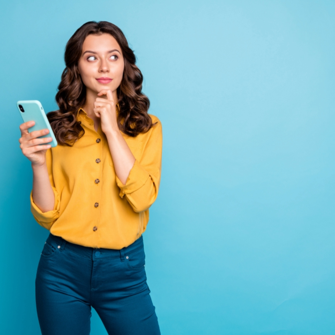 A smiling woman in a yellow sweater uses her smartphone while holding a credit card, highlighting the ease of online ordering, self-registration, and secure payment options.